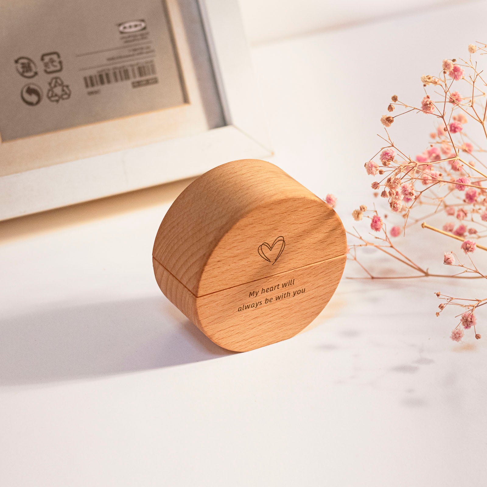 Round wooden keepsake urn side view – engraved heart and "My heart will always be with you", natural wood grain with visible magnetic seam, displayed with dried flowers and frame